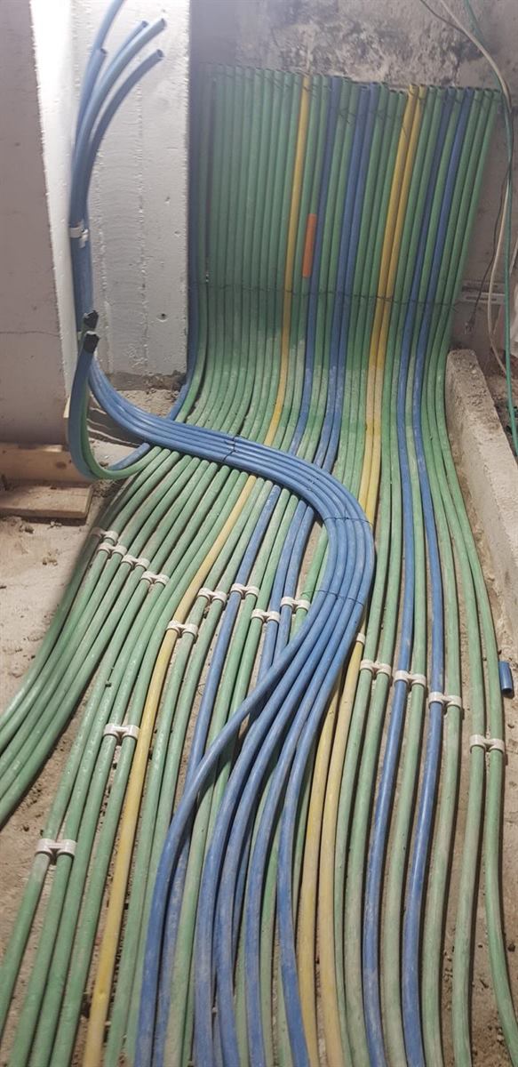 צנרת ירוקה וכחולה מסודרת על הרצפה בשלב השלד ומחוזקת בתפסים